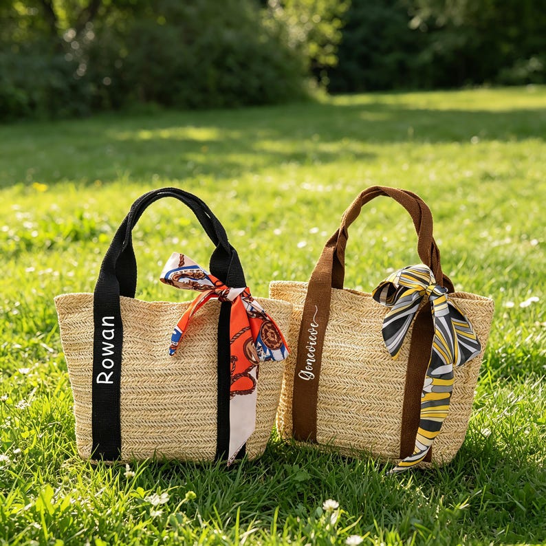 May include: Two straw tote bags with black and brown handles, personalized with names. Each bag features a colorful scarf tied to the handle. One bag has the name "Rowan" and the other has the name "Genevieve".
