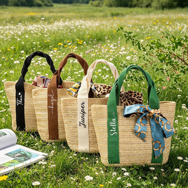 May include: Four woven straw tote bags with different colored handles and ribbons. Each bag has a name printed on the ribbon: Thea, hazel, Juniper, and Stella. The bags are decorated with scarves and bows.