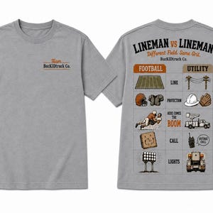 May include: A heather gray short-sleeve t-shirt featuring a small logo on the front chest that reads Team BucKIDtruck Co. The back displays a comparison chart titled LINEMAN VS LINEMAN with illustrations of football and utility work gear.