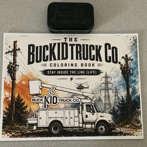 May include: A rectangular coloring book titled The Buckid Truck Co. Coloring Book Stay Inside The Line (Life) featuring a white utility bucket truck, utility poles with workers, and a helicopter, positioned below a small black rectangular metal tin.