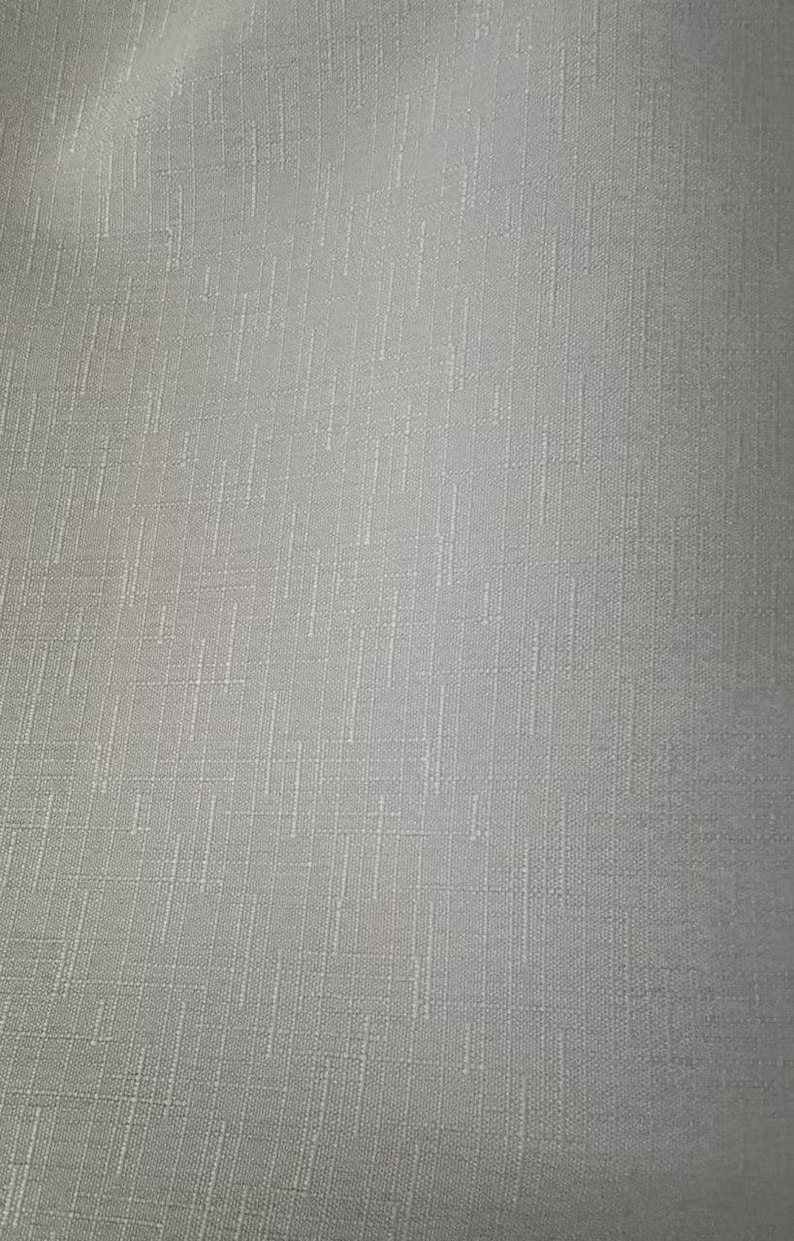 May include: Close-up of a textured, light gray fabric. The material has a subtle, woven pattern with vertical and horizontal lines, creating a grid-like appearance. The fabric appears to be a medium weight, suitable for various textile projects.