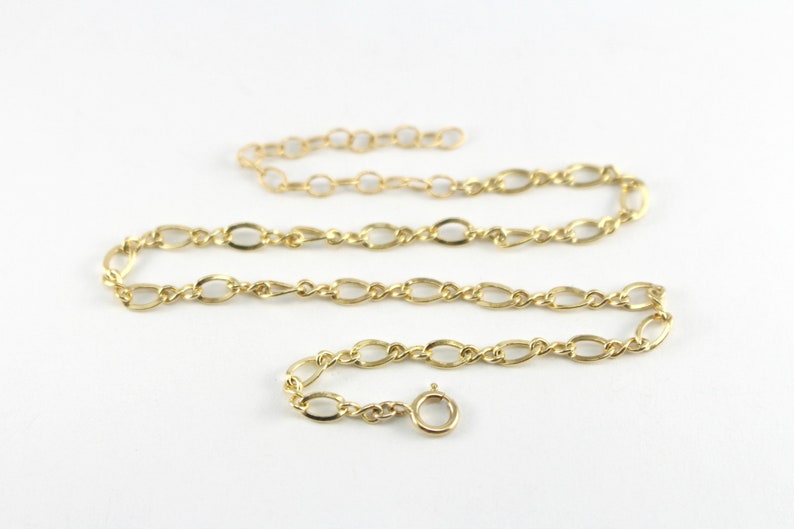 May include: A gold chain necklace with a lobster clasp closure. The chain is made of oval links.