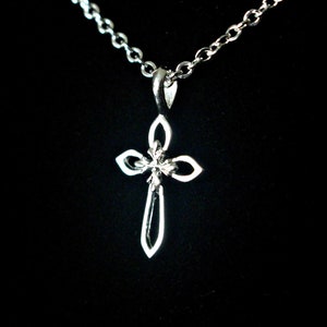 May include: A silver chain necklace with a small, detailed silver cross pendant.