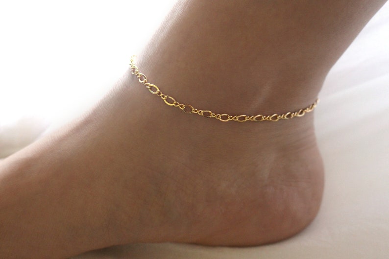 May include: A gold chain anklet with a delicate, oval-shaped link design.