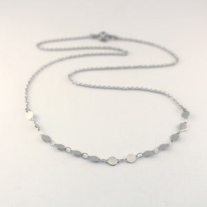 May include: A silver chain necklace with small, round silver charms.