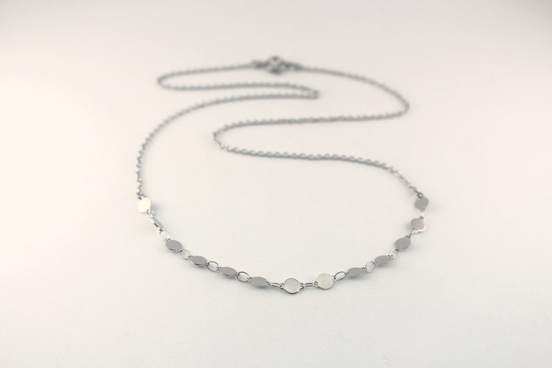 May include: A silver chain necklace with small, round silver charms.