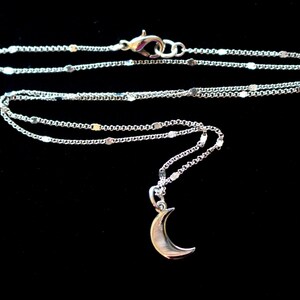 May include: A silver chain necklace with a crescent moon pendant.