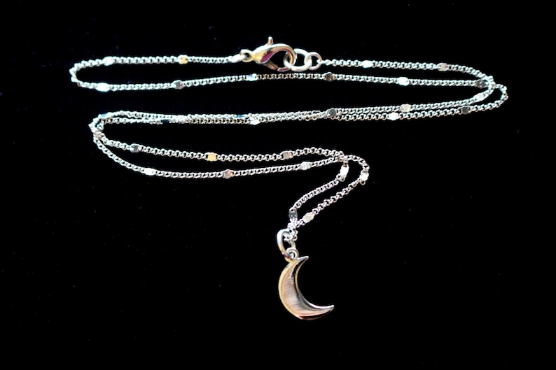 May include: A silver chain necklace with a crescent moon pendant.