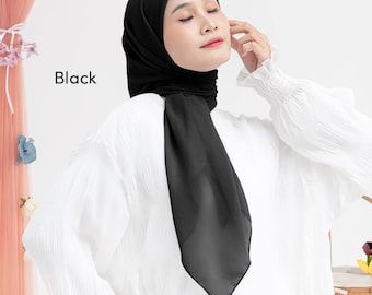 May include: A black hijab, a head covering, is draped over the head and shoulders. The word "Black" is printed on the left side of the image. The hijab is paired with a white blouse with textured sleeves.