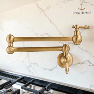 Puede incluir: Un grifo de llenado de ollas de color latón, montado en la pared con un diseño de brazo oscilante. El grifo tiene un estilo clásico y elegante con un mango de palanca y una base redonda. La marca "Brass Harbor" es visible.
