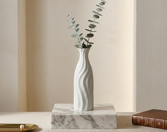 Vaso per fiori singoli in ceramica bianca con superficie ondulata, complemento d'arredo moderno e minimalista.