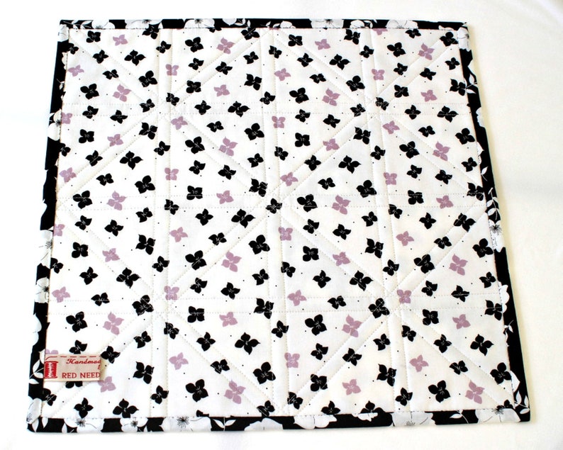 One layer cotton batting is sandwiched between the front and back. The back features black and lavender flowers on white. Black and white floral binding is handsewn to the back for a neat finish.