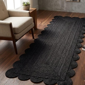 May include: A rectangular black runner rug featuring a braided texture and a scalloped edge design. The rug is constructed with a woven pattern that creates a consistent dark surface, extending across the floor with rounded edges along the perimeter.
