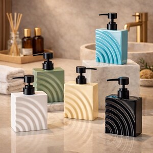 Può includere: Un set di cinque dispenser di sapone quadrati in ceramica, bianchi, verdi, gialli, blu e neri. Ogni dispenser ha una pompa nera e un design a onde. Perfetti per l'arredo bagno.
