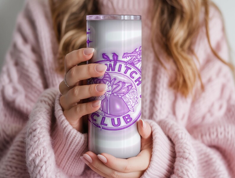 May include: A tall, cylindrical tumbler with a purple and white design. The tumbler features the words "Witch Club" in a circular design, along with a witch illustration and a dragon. The tumbler is held by a person wearing a pink sweater.