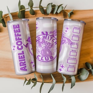 May include: Three insulated tumblers with purple and white designs. One tumbler reads "ARIEL COFFEE", another features a "BAD WITCH CLUB" logo, and the third has a coffee order form. The tumblers are decorated with stars and dragon illustrations.