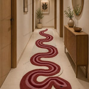 Può includere: Un lungo tappeto decorativo in un corridoio, con un design a serpente. Il tappeto ha uno sfondo color crema con un motivo a serpente sinuoso in tonalità di rosso e rosa. La testa del serpente è alla fine del tappeto.