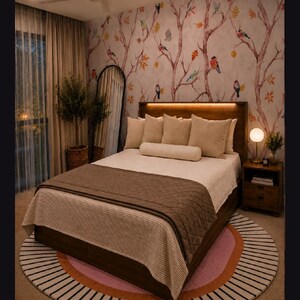 May include: A bedroom featuring a wooden bed frame with integrated headboard lighting, dressed in beige pillows and a brown quilted runner. The room includes a round rug with pink and orange bands, a floor mirror, and wallpaper with bird motifs.