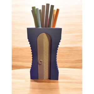 May include: A blue pencil sharpener with a gray sharpening blade and a holder for pencils. The sharpener has a textured design and a screw in the center of the blade. There are multiple colored pencils in the holder.