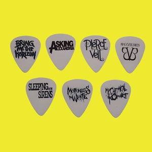 May include: Set of eight white guitar picks with black band logos. The bands include Bring Me The Horizon, Asking Alexandria, Pierce The Veil, Black Veil Brides, Sleeping With Sirens, Motionless In White, My Chemical Romance.