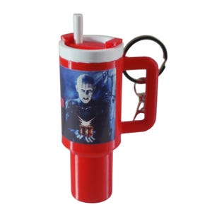 May include: A red plastic travel mug with a white rim and a black handle. The mug features a graphic of a character from a horror movie. The mug has a white straw and a black keyring attached to the handle.