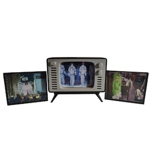 Puede incluir: Un televisor retro en blanco y negro con tres imágenes. La imagen central muestra a tres personas con monos blancos. Las otras dos imágenes muestran escenas con un hombre de malvavisco gigante y un fantasma verde.
