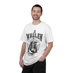 May include: White t-shirt featuring a black and white graphic of a guitar with the text "Wallen Nashville Tennessee". The design includes wings and stars, creating a vintage, music-themed aesthetic.