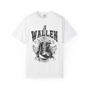 May include: White t-shirt featuring a distressed black graphic of an electric guitar with wings, the word "WALLEN" above, and "NASHVILLE TENNESSEE" below. The shirt is a classic crew neck style.