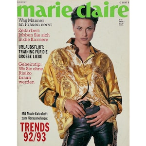 Könnte beinhalten: Das Cover des Marie Claire Magazins zeigt eine Frau in einem goldfarbenen Hemd mit Muster und einer schwarzen Lederhose. Der Titel des Magazins ist grün, mit deutschen Schlagzeilen und dem Datum der Ausgabe. Das Cover enthält auch den Text "TRENDS 92/93."