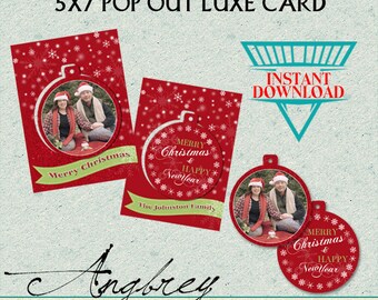 May include: A printable 5x7 inch pop-out Christmas card with a red background and a white snowflake pattern. The card features a photo of a couple in a circle with the text "Merry Christmas" on a green banner. The card also includes a red ornament with the text "Merry Christmas & Happy New Year" in gold lettering. The card is designed for instant download.