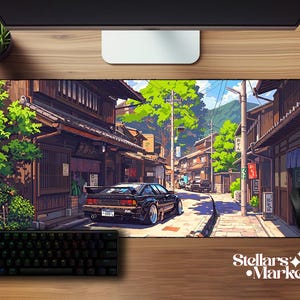 May include: A rectangular desk mat featuring a detailed illustration of a black sports car parked on a narrow street in a Japanese town. The scene includes traditional wooden buildings, lush green trees, utility poles, and a clear blue sky.
