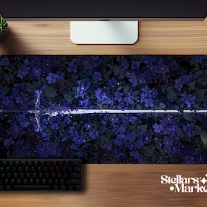Op de afbeelding: Een rechthoekige muismat met een bloemenpatroon van blauwe bloemen en groene bladeren. Een wit zwaardmotief is gecentreerd. Een zwart toetsenbord en muis zijn zichtbaar. De tekst "Stellars Market" staat rechtsonder.