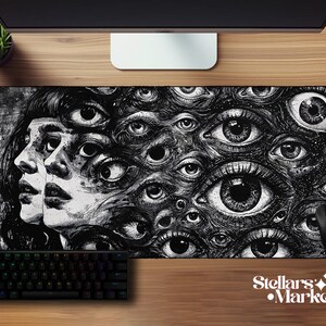May include: A rectangular desk mat featuring a black and white ink-style illustration of two side-profile faces surrounded by a dense, overlapping pattern of numerous human eyes of varying sizes, creating a surreal and intricate visual composition.