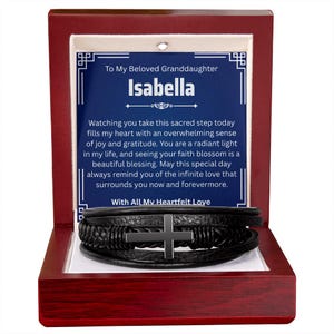 May include: A black leather bracelet with a silver cross is displayed inside a wooden box. The box contains a card with the text "To My Beloved Granddaughter Isabella" and a heartfelt message. The box is red with a white interior.
