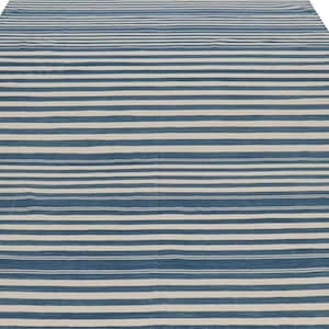 May include: A large, rectangular rug with a striped pattern. The rug features alternating horizontal stripes of blue and off-white, creating a simple yet visually appealing design. The rug is made of a woven material.