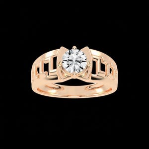 Könnte beinhalten: Roségoldener Ring mit einem großen, runden, klaren Edelstein. Das Band hat ein offenes Design mit geometrischen Formen. Der Ring ist vor einem schwarzen Hintergrund platziert, der sein Funkeln und seine komplizierten Details hervorhebt.