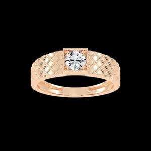 Könnte beinhalten: Roségoldener Ring mit einem quadratisch gefassten, rund geschliffenen Diamanten. Das Band weist ein strukturiertes, gestepptes Muster auf. Der Ring ist vor einem schwarzen Hintergrund platziert. Ein klassisches Schmuckstück.