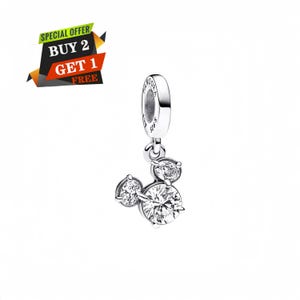 May include: A silver charm with a Mickey Mouse design, featuring three clear, sparkling cubic zirconia stones. The charm has a loop at the top for attachment. The image also includes a promotional banner that says "SPECIAL OFFER BUY 2 GET 1 FREE".