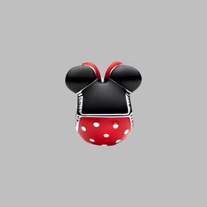 Puede incluir: Un charm con forma de cabeza de Minnie Mouse. El charm presenta orejas negras, una falda roja con lunares blancos y una parte superior negra. El charm es de metal y tiene la palabra "Disney" grabada en el lateral.