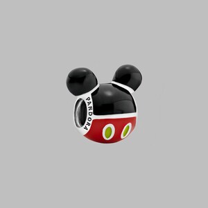 May include: A charm in the shape of Mickey Mouse's head. The charm is black and red with two black spheres for ears. The charm has the word "PANDORA" printed on it and two green ovals for eyes.