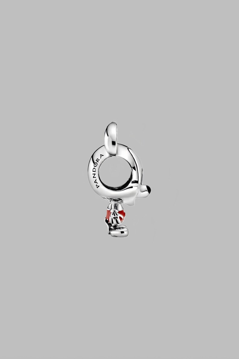 Peut inclure: Un charm en argent avec une boucle, repr&eacute;sentant un personnage de dessin anim&eacute; avec une tenue rouge et blanche. Le charm porte l'inscription "Pandora". Le visage du personnage est blanc avec un nez noir.
