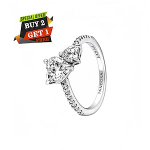 Peut inclure: Une bague en argent ornée de deux pierres transparentes en forme de cœur côte à côte. L'anneau est décoré de petites pierres transparentes sur les côtés et porte les inscriptions S 925 ALE et PANDORA gravées sur la face interne de l'anneau.