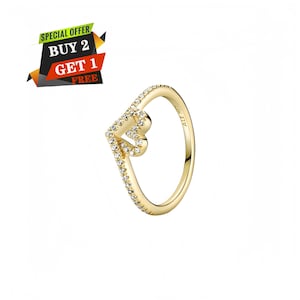 May include: A gold-tone ring featuring a V-shaped band with a heart-shaped cutout at the top, accented with small clear stones along the outer edge. The inner band is engraved with the text ALE MET.