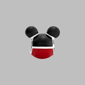 May include: A Mickey Mouse-shaped charm with black ears, a black head, and a red lower face. The charm has white accents and the words "DISNEY" and "ALE 925" printed on it. The charm is set against a gray background.