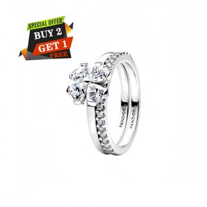 May include: A silver-toned ring featuring a four-leaf clover design composed of four heart-shaped clear stones. The band is accented with a row of small clear stones and engraved with the text PANDORA. A graphic overlay reads SPECIAL OFFER BUY 2 GET 1 FREE.