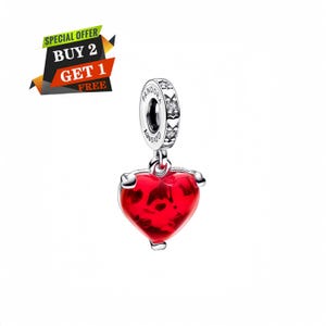 Puede incluir: Un charm de plata con un colgante en forma de coraz&oacute;n rojo. El charm tiene una banda decorativa con piedras transparentes y las palabras "Pandora" y "Disney" grabadas. Un banner de "Oferta especial" est&aacute; en la esquina superior izquierda.