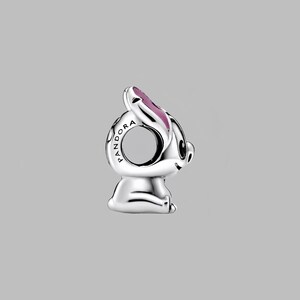 May include: A silver-colored charm in the shape of a cartoon bunny with pink accents on the ears. The charm has the word "PANDORA" engraved on the side. The bunny is sitting down with its head tilted slightly.