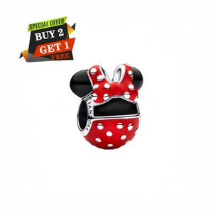Puede incluir: Un charm rojo con lunares blancos con forma de la cabeza de Minnie Mouse. El charm tiene orejas negras y un lazo rojo con lunares blancos. El charm es un producto de la marca Pandora.