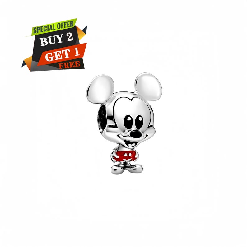 Peut inclure: Un charm argent&eacute; Mickey Mouse avec une tenue rouge et blanche. Le charm a de grands yeux noirs et un visage souriant. L'image comprend &eacute;galement une banni&egrave;re qui dit "OFFRE SP&Eacute;CIALE ACHETEZ 2 OBTENEZ 1 GRATUIT".