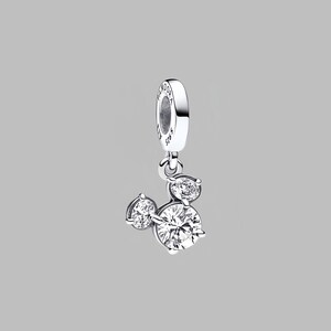 May include: A silver charm featuring three clear cubic zirconia stones, forming a Mickey Mouse head shape. The charm has a loop for attaching to jewellery. The background is a plain grey.